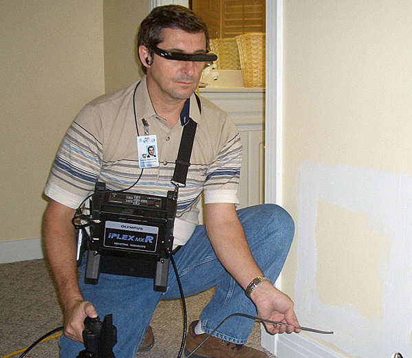 Technician Using Snake Cam Examines Moisture In Wall